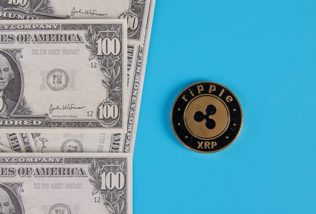 Ripple XRP and US dollars. Digital currency close-up. Virtual money. Crypto currency. Metal coin of XRP, banknotes of one hundred dollars.