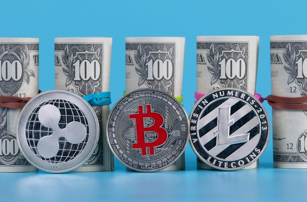 Silver XRP Bitcoin BTC Litecoin coins and stack of one hundred US dollar banknotes
